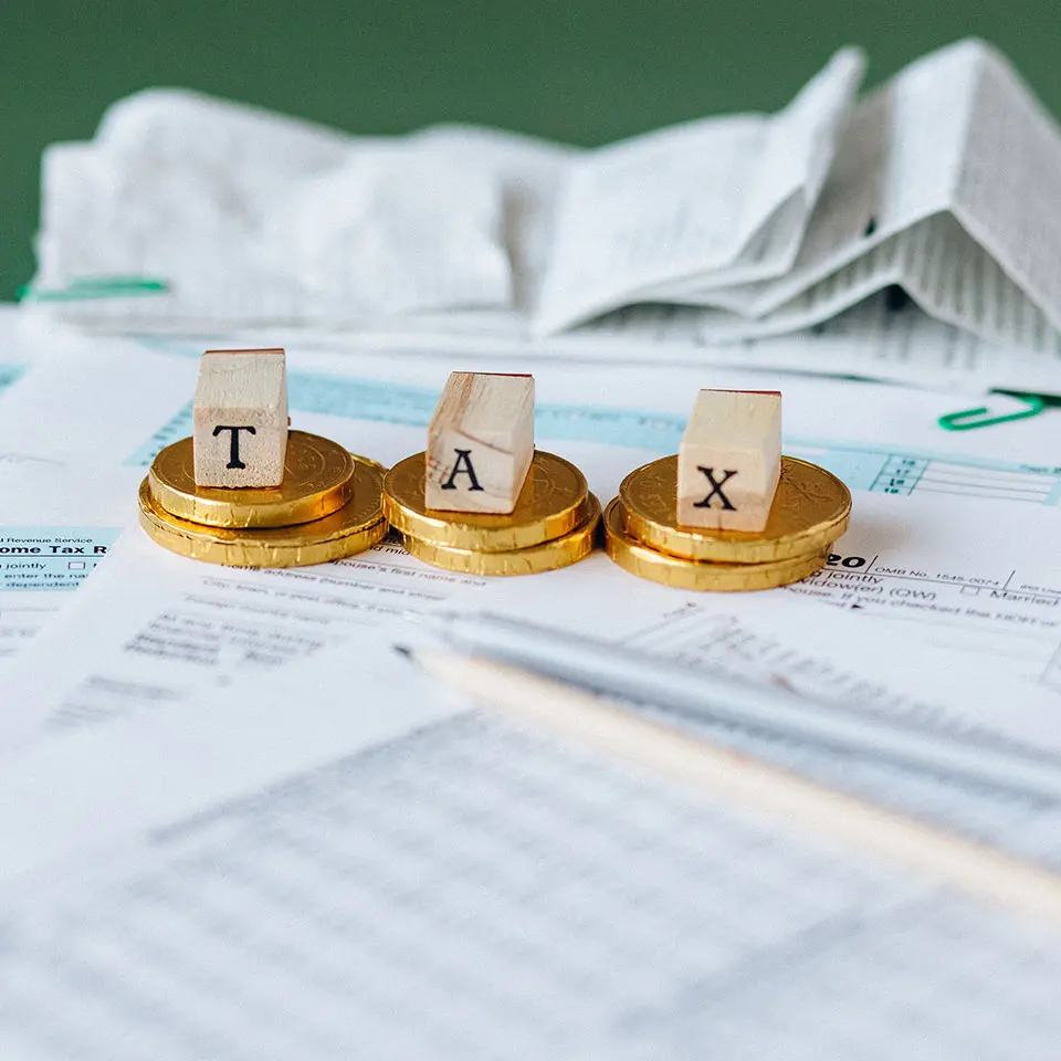 Word TAX Composed of Wooden Letters. Coins, Papers, Pens in the Background