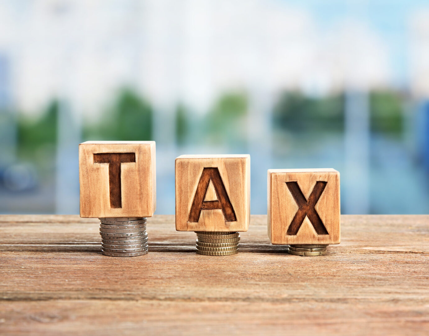 Word tax on wooden blocks with stacked coins. Financial concept.